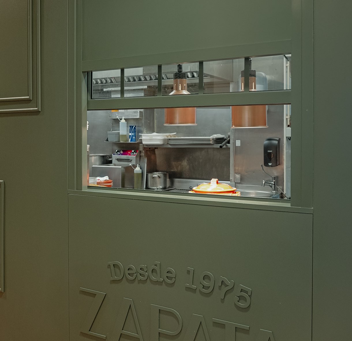 Janela para a cozinha na parede verde com o logótipo Zapata