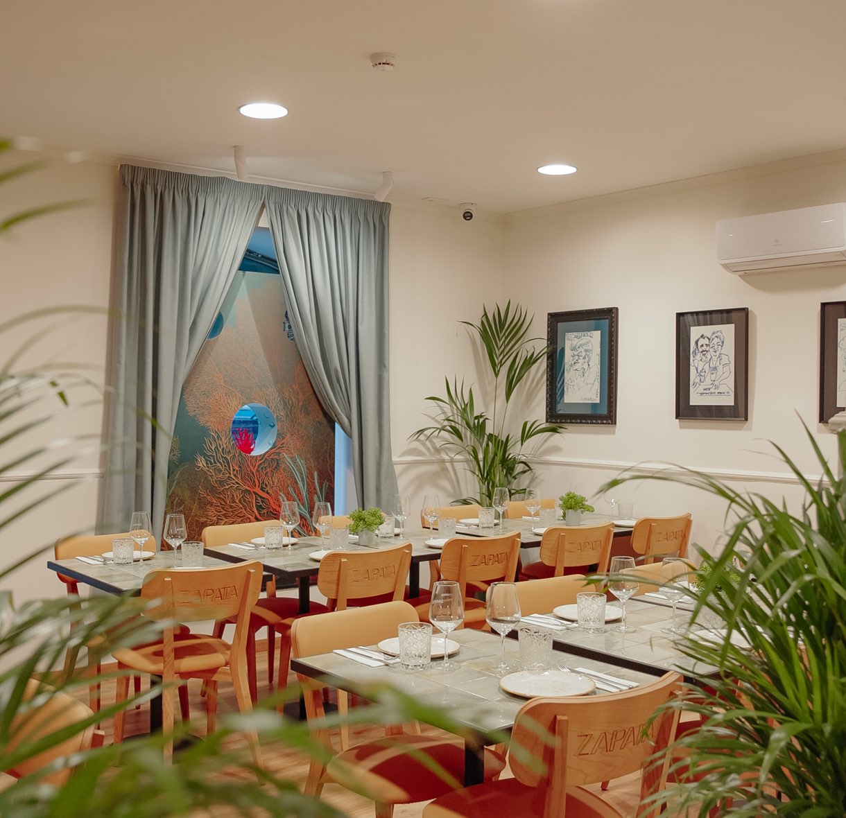 Sala de refeições com mesas postas e plantas