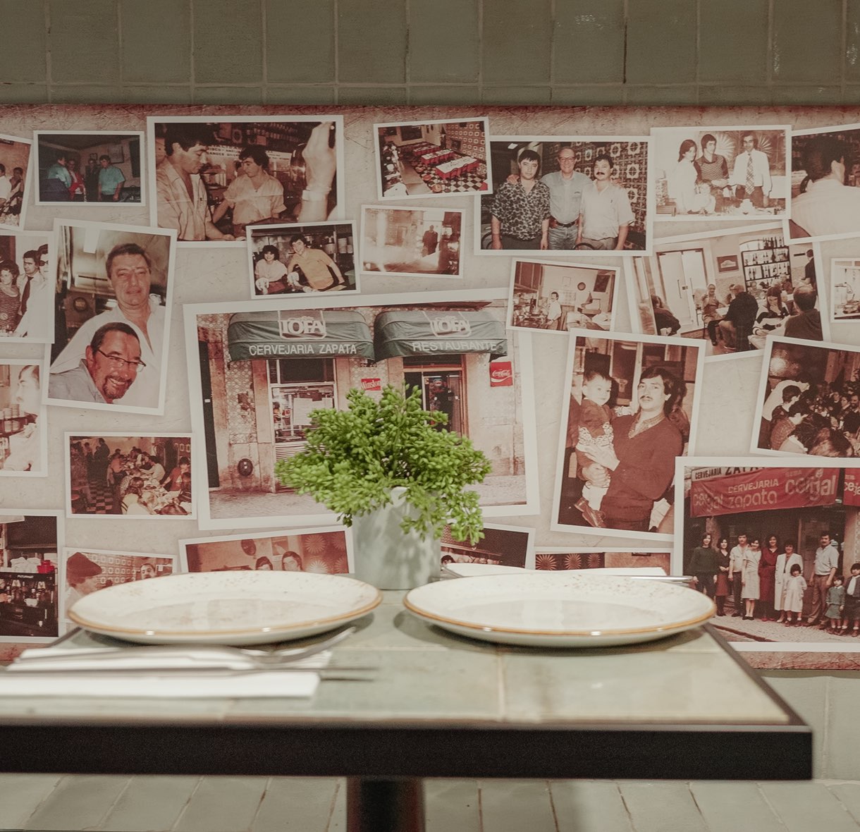 Mesa posta junto à parede de fotografias antigas das famílias da Cervejaria Zapata