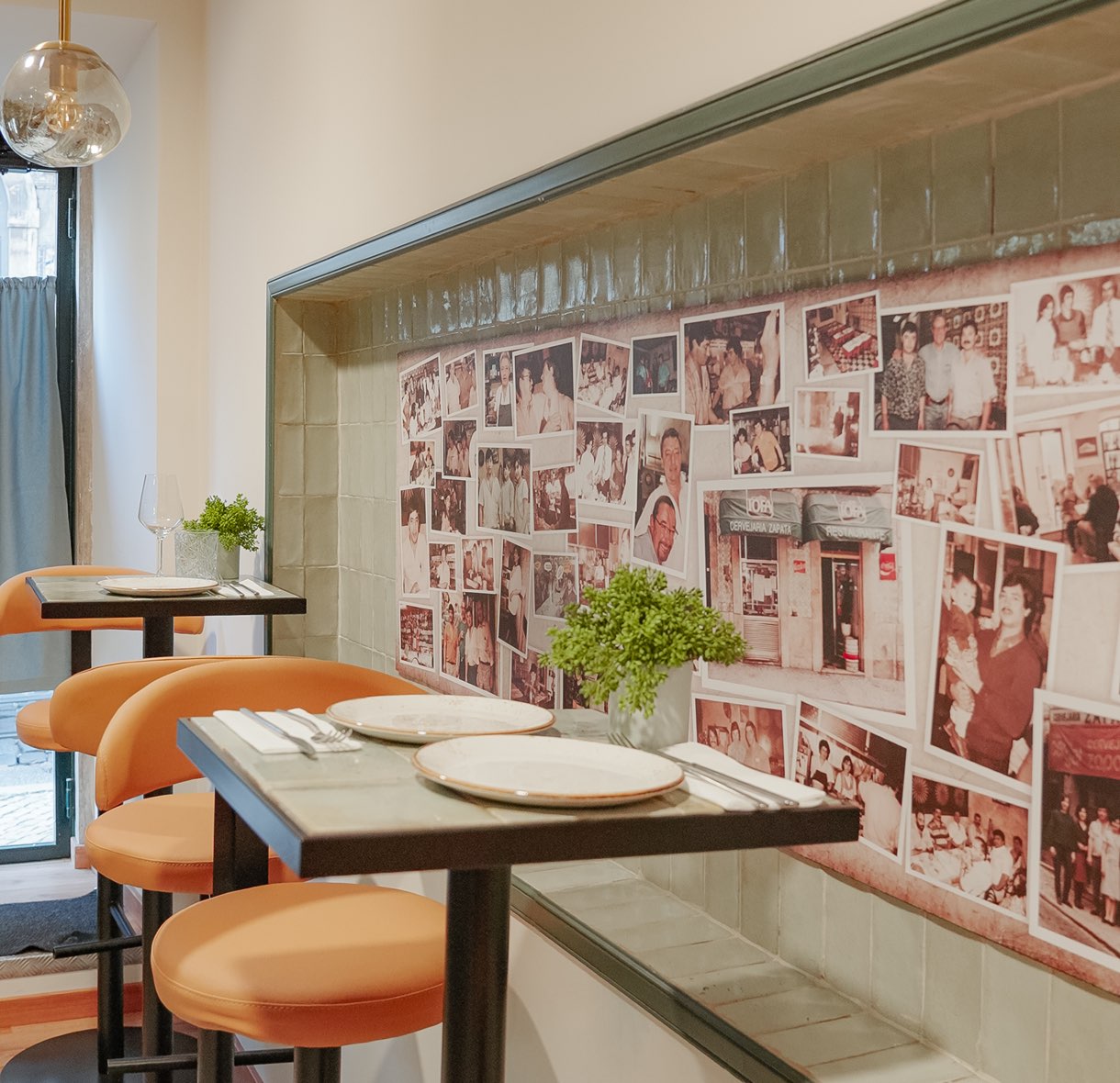 Sala com mesas postas e parede coberta de fotografias de família